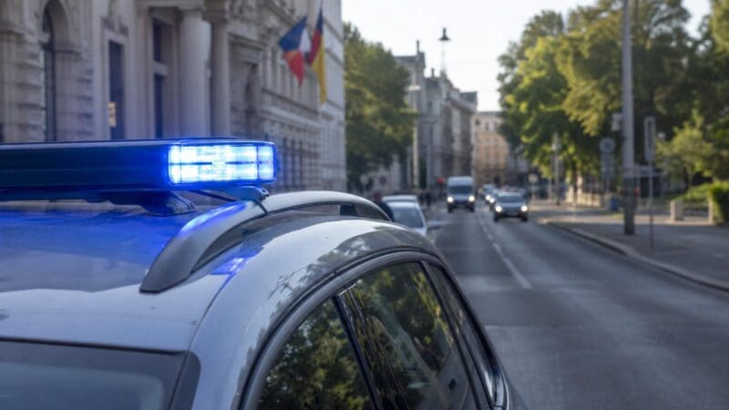 Polizeifahrzeug mit aktiviertem blauen Blaulicht auf dem Dach in einer Stadtstraße