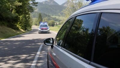 Polizeifahrzeug im Vordergrund und zweites Fahrzeug mit Blaulicht auf einer Landstraße in den Bergen