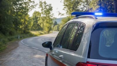 Heckansicht eines Polizeifahrzeugs mit Blaulicht auf einer Landstraße