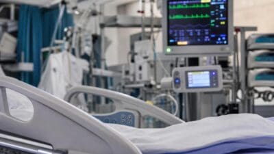 Krankenbett und Herzmonitor mit Vitalwerten auf einer Intensivstation