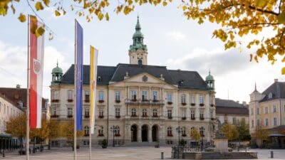 Historisches Rathaus mit grünem Turm, davor Flaggen auf dem Platz im Herbst in Klagenfurt.