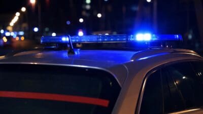 Nahaufnahme eines Polizeifahrzeugs mit aktiviertem blauen Blaulicht auf dem Dach in der Nacht
