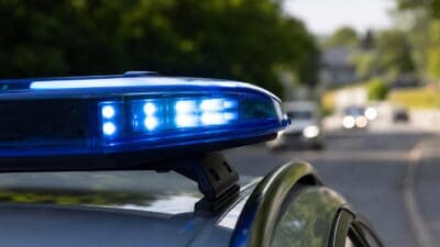 Nahaufnahme eines blauen Blaulichts auf dem Dach eines Polizeifahrzeugs an einer Straße