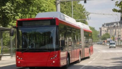 Roter Gelenkbus fährt auf einer breiten Straße in der Stadt