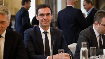 Markus Wallner sitzt in dunklem Anzug an einem Konferenztisch mit verschränkten Händen.