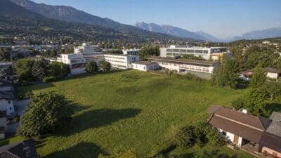 Weite grüne Wiese vor Schulgebäuden mit Bergpanorama im Hintergrund in Telfs