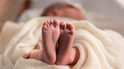 Die Füße eines Neugeborenen ragen aus einer weißen Decke hervor