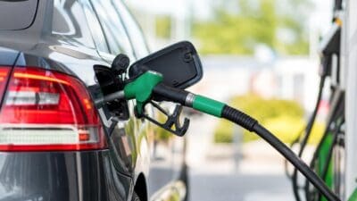 Grüne Zapfpistole wird in den Tank eines schwarzen Autos an einer Tankstelle gesteckt