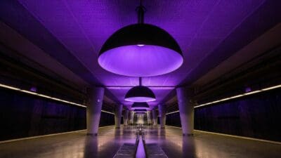 Leere U-Bahn-Station mit violetter Beleuchtung und großen schwarzen Lampenkuppeln in Wien