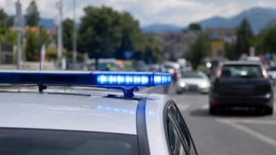 Blaues Blaulicht leuchtet auf dem Dach eines weißen Polizeifahrzeugs auf einer Straße