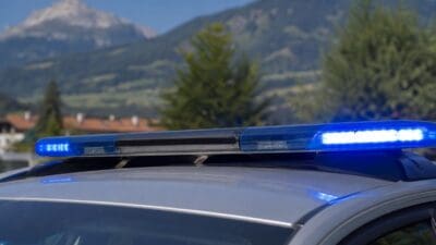 Leuchtender Blaulichtbalken auf dem Dach eines Polizeifahrzeugs vor Berglandschaft in Tirol.