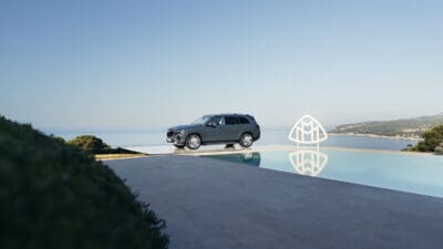 Grauer Mercedes-Maybach GLS SUV auf einer Plattform neben einem Infinity-Pool mit Meerblick