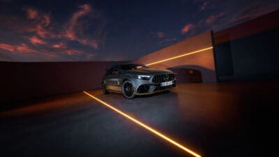 Grauer Mercedes-AMG A 45 S in moderner Halle mit orangefarbenen Lichtlinien auf dem Boden und der Wand