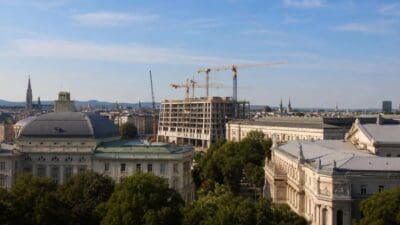Blick auf historische Wiener Gebäude und eine Baustelle mit Kränen unter klarem Himmel
