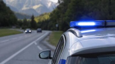 Polizeifahrzeug mit blauem Blaulicht auf einer Straße vor Bergen