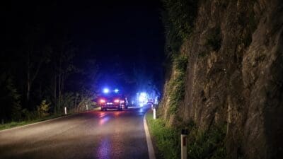 Polizeifahrzeug mit Blaulicht auf nächtlicher Straße neben Felswand nach Unfall bei Schwoich