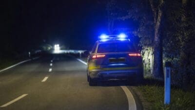 Polizeifahrzeug mit Blaulicht auf einer nächtlichen Landstraße