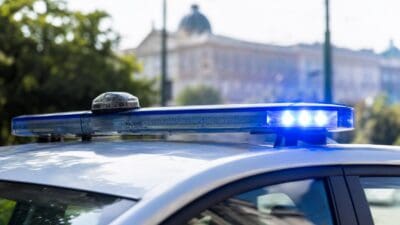 Blaues Blaulicht leuchtet auf dem Dach eines Polizeiautos vor unscharfen Gebäuden