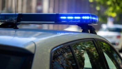 Nahaufnahme eines Polizeifahrzeugs mit leuchtendem blauen Blaulichtbalken und Antenne auf dem Dach.