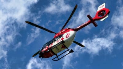 Roter und weißer Rettungshubschrauber der ARA Flugrettung mit Kennung OE-XRE vor blauem Himmel
