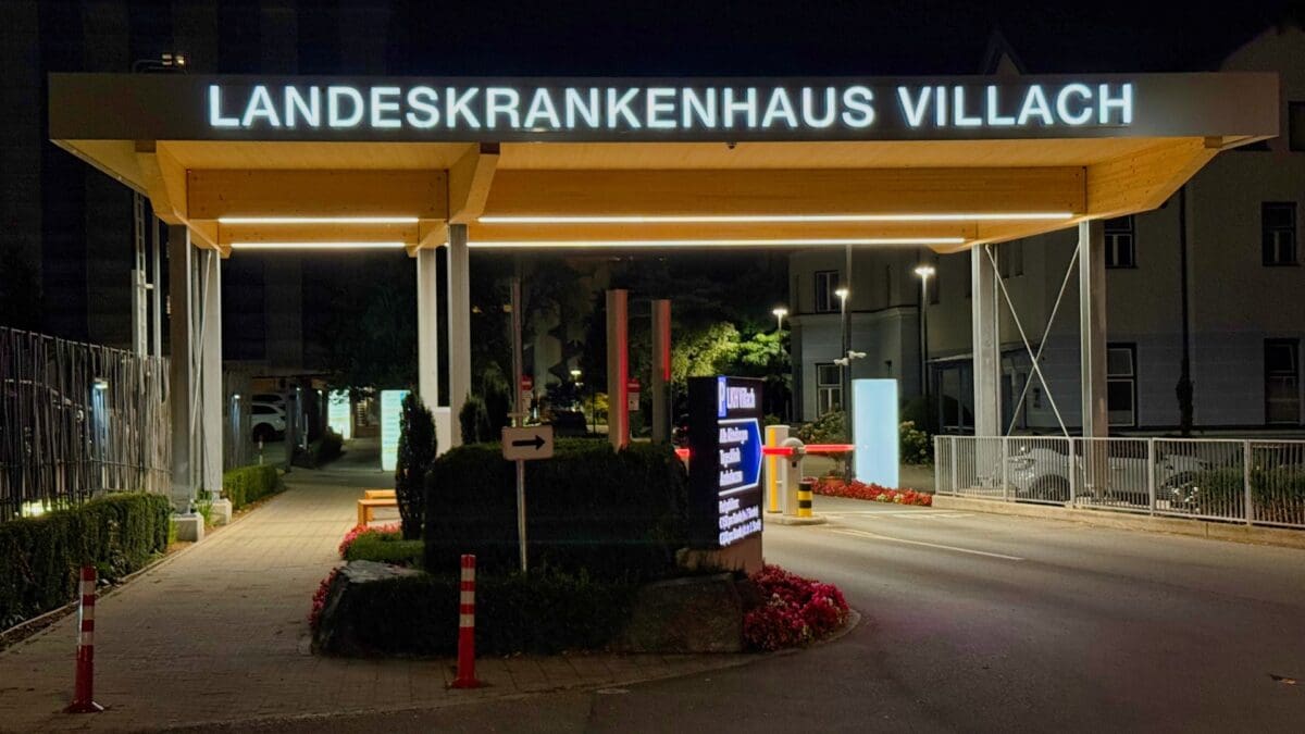 Nächtliche Ansicht des Eingangs zum Landeskrankenhaus Villach mit leuchtendem Namensschild