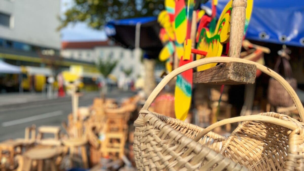 Geflochtener Korb im Vordergrund vor bunten Holzspielzeugen und Holzstühlen auf dem Laurentiusmarkt