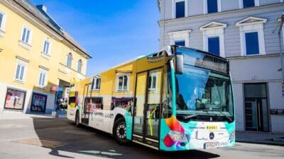 Ein gelb-türkiser Bus der Kärntner Linien auf einer Straße in Villach.