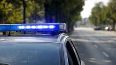 Nahaufnahme eines Polizeifahrzeugs mit leuchtendem blauen Blaulichtbalken auf einer Straße