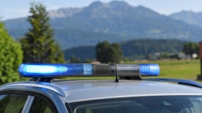 Blaues Blaulicht auf dem Dach eines Polizeifahrzeugs vor einer Berglandschaft