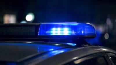 Nahaufnahme eines leuchtenden blauen Blaulichts auf dem Dach eines Polizeifahrzeugs bei Nacht