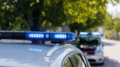 Nahaufnahme eines aktivierten blauen Blaulichts auf einem Polizeifahrzeug mit einem zweiten Wagen im Hintergrund