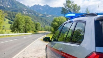 Polizeifahrzeug mit eingeschaltetem Blaulicht auf einer Landstraße in den Bergen