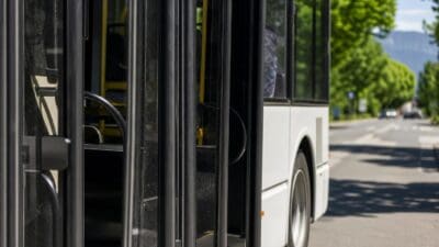 Geöffnete Türen eines weißen Busses mit Blick in den Innenraum und gelbe Haltestangen