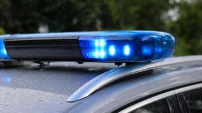 Blaues Blaulicht einer Polizeileuchte leuchtet auf dem Dach eines regennassen Autos