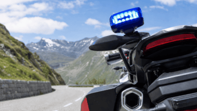 Heck eines Motorrads mit blauem Blaulicht vor schneebedeckten Bergen auf einer Passstraße