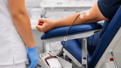 Eine Person spendet Blut in einem modernen Klinikraum während eine Pflegekraft den Vorgang überwacht.