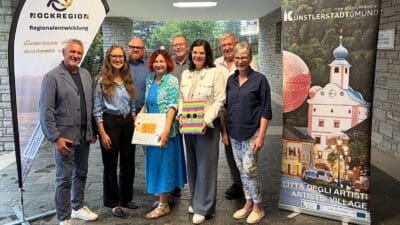 Gruppe von sieben Erwachsenen mit Bannern der Nockregion und bunten Schildern