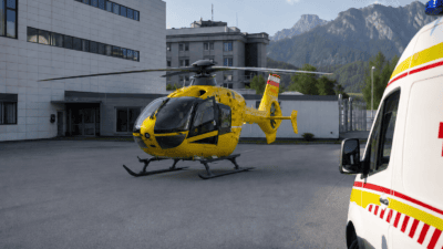 Gelber Rettungshubschrauber mit geöffneter Tür auf dem Helipad neben einem Rettungswagen