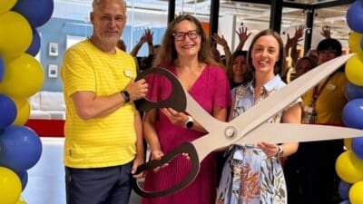Drei Personen halten eine große Schere bei der Eröffnungsfeier in einem Möbelhaus.