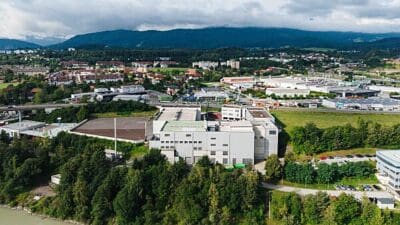 Luftaufnahme des Biomasseheizkraftwerks Untere Fellach mit umgebenden Wäldern und Gebäuden in Villach