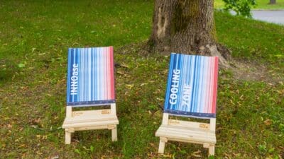 Zwei gestreifte Klappstühle mit Aufschriften INNOase und Cooling Zone auf einer Wiese