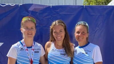 Drei Frauen des LC Villach in Laufbekleidung lächeln vor einer blauen Wand in Velden.