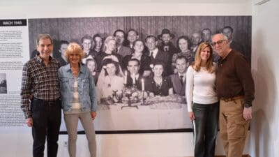 Vier Erwachsene stehen vor einer großen historischen Fotografie in einer Ausstellung.