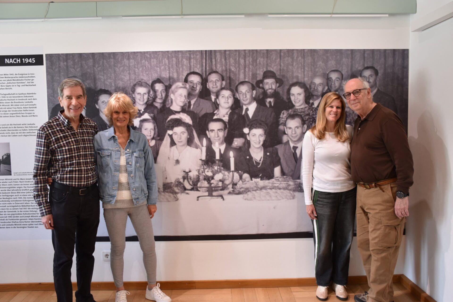 Vier Erwachsene stehen vor einer großen historischen Fotografie in einer Ausstellung.
