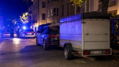 Polizeibeamte und Streifenwagen mit Blaulicht neben einem Pkw mit Anhänger bei Nacht in Innsbruck