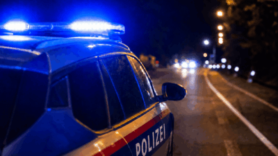 Seitenansicht eines Polizeifahrzeugs mit leuchtendem Blaulicht auf dem Dach bei Nacht