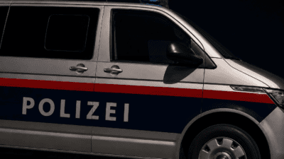 Seitenansicht eines silbernen Polizeivans mit blauem Blaulicht und POLIZEI-Schriftzug in der Nacht
