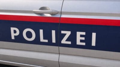 Nahaufnahme der Tür eines silbernen Polizeiautos mit der Aufschrift POLIZEI auf blauem Grund.