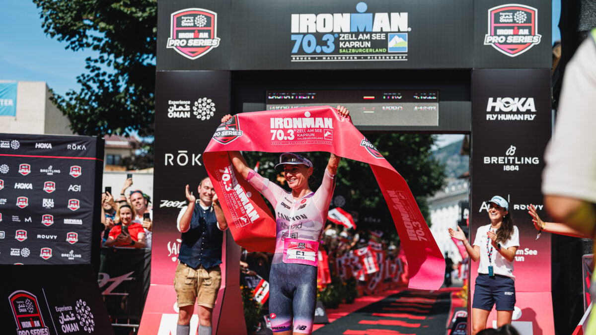 Laura Philipp hält das rote Siegerband über dem Kopf am IRONMAN 70.3 Ziel hoch.