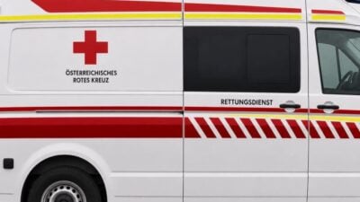 Seitenansicht eines weißen Rettungswagens des Österreichischen Roten Kreuzes mit rotem Kreuz und Aufschrift